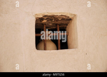 A terracotta jar behind a window in the fort of Nizwa in Oman. Stock Photo