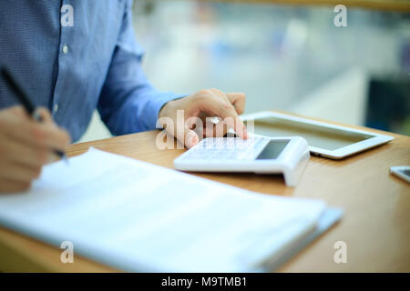Man using calculator to count income and outcome. Stock Photo