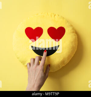 Emoji as soft yellow pillow on yellow background. Close up. Pattern Stock Photo