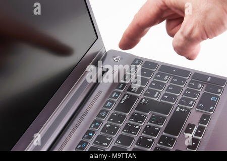 Silver laptop and moving man's hand catching start button, isolated on white background Stock Photo