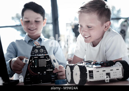 Smart schoolboys working with self automated robots in workshop Stock Photo