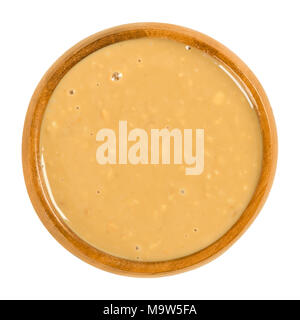 Crunchy peanut butter in wooden bowl. Food paste or spread. Made from ground dry roasted peanuts. Arachis hypogaea. Groundnuts or goober. Stock Photo