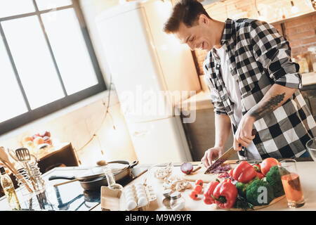 Beautiful happiness man making salad at home, gets pleasure from the fact that he cooks. Indoor, studio shot Stock Photo