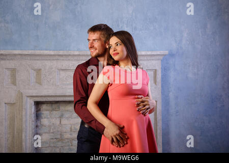 Husband hugs a pregnant wife. He strokes her belly. Happiness of parenthood. Stock Photo