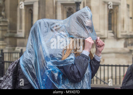 London, UK. 29th March 2018. Pedestrians share a rain poncho in Westminster as London is hit by heavy rain showers Credit: amer ghazzal/Alamy Live News