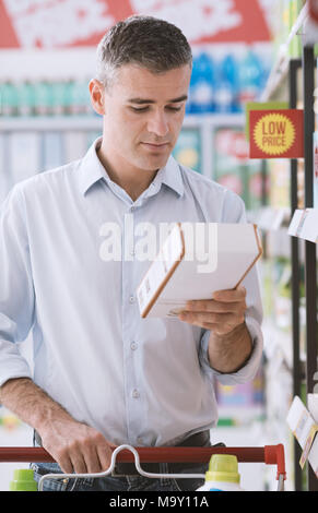 Man doing grocery shopping at the supermarket and reading a food label on a box, shopping and nutrition concept Stock Photo