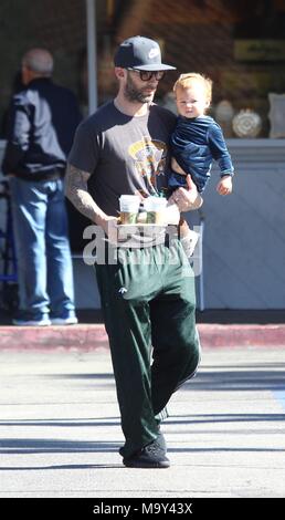 Adam Levine picks up coffee while holding his daughter Dusty Rose