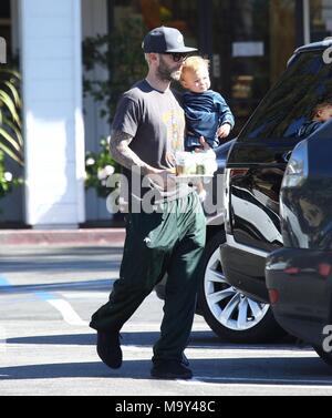 Adam Levine picks up coffee while holding his daughter Dusty Rose