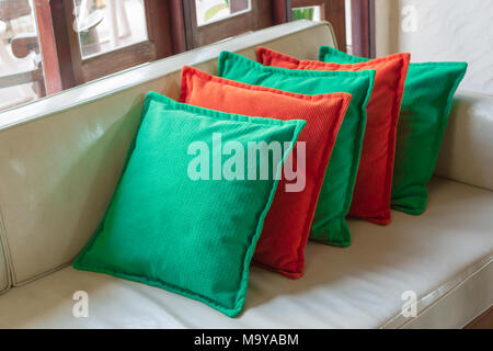 Orange and green Decorative pillows on white leather sofa Stock Photo
