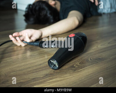 Hair dryer electric shock, accident of man pass out on the floor Stock Photo
