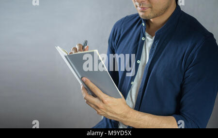 Man writing on notebook on grey background Stock Photo