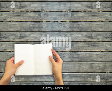 Opened notebook hand holding on wooden wall Stock Photo