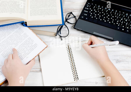 Workplace with blank monitor, notepad and pen in his hand,  and many books on it to the left, office, concept of work,  top view Stock Photo