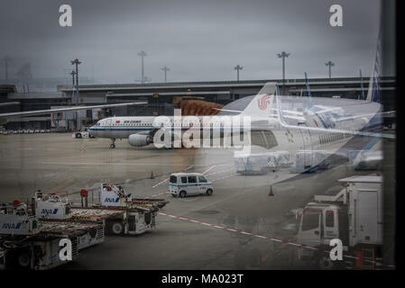 Reflection of plane in window of airport with equipment in background Stock Photo