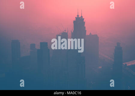 Dubai at dusk, cityscape with high-rise towers in the fog over beautiful pink sunset background Stock Photo