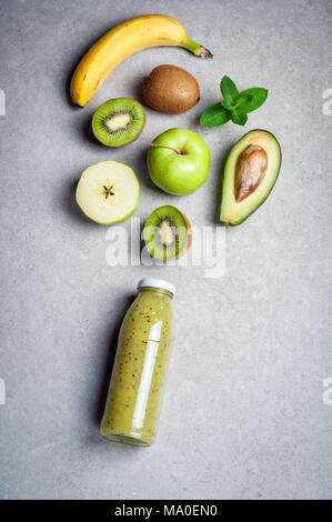 Healthy green smoothie and ingredients on grey background. Kiwi smoothie with fruits banana, avocado and apples. Superfoods, diet, detox, health, vege Stock Photo