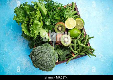 Green vegetables background. Fresh garden produce. Broccoli, spinach, kiwi, lettuce, parsley, dill, asparagus beans, lime on blue concrete background, Stock Photo