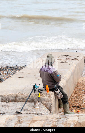 A metal detectorist takes a break resting on Ramsgate beach. Stock Photo