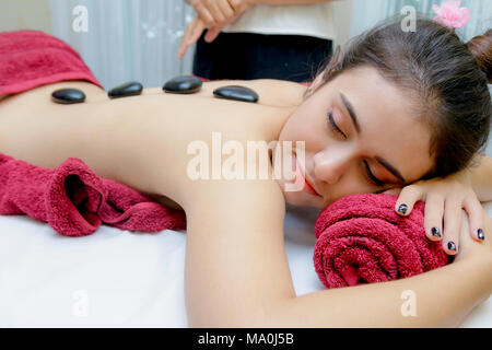 Hot stone massage therapy,Young woman getting hot stone massage in spa salon Stock Photo