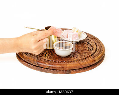 Turkish coffee is served in a traditional manner. A woman’s hand is offering rahat lokum to you to fulfill your coffee drinking experience. Stock Photo