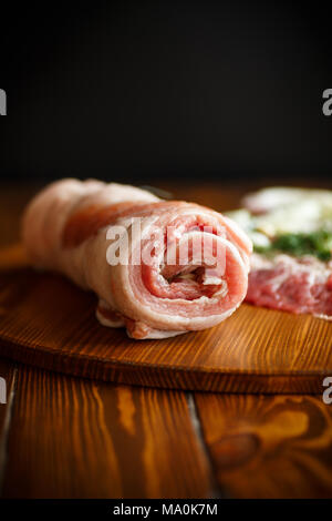 Roll of meat with various spices and herbs on a wooden table Stock Photo