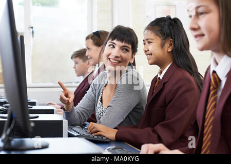 Pupils Wearing Uniform In Computer Class With Female Teacher