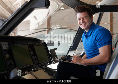 Portrait Of Male Aero Engineer With Clipboard Working In Helicopter Cockpit Stock Photo