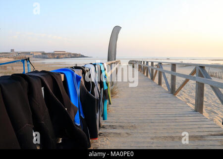 Neoprene costumes hanging on the wooden path to Tarifa beach, Spain Stock Photo