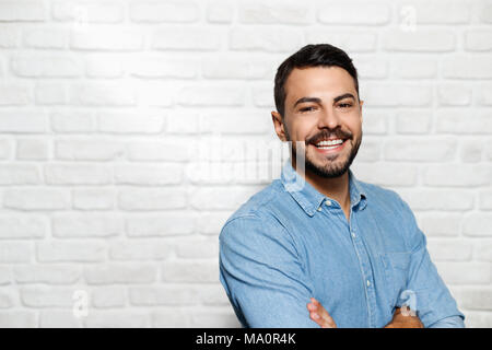 Portrait of happy Italian man smiling against white wall as background and looking at camera. Stock Photo