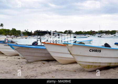 Three motorboats parked on sandy beach with sailboats in the distance. Stock Photo
