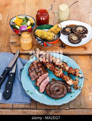 Corn cobs and meat, chicken tikka skewers and barbecued steaks at The Backyard Grill Lounge, Sea Point, South Africa Stock Photo