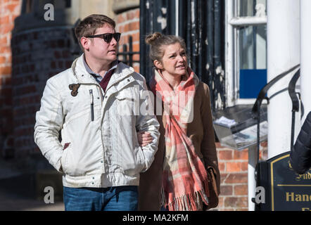Young couple dressed in warm clothes walking through a small town linking arms in Winter in the UK. Stock Photo