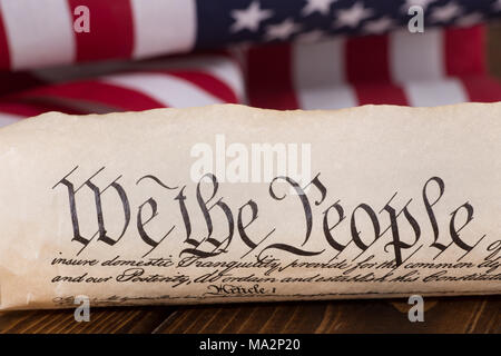 Document text 'We the People' of the preamble to the United States constitution with american flag in background Stock Photo