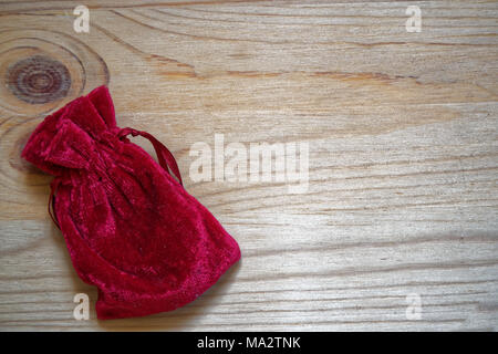 Postcard sample, grenadine gift pouch on wooden background with free copyspace for greeting text. Stock Photo