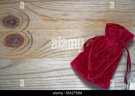 Postcard sample, grenadine gift pouch on wooden background with free copyspace for greeting text. Stock Photo