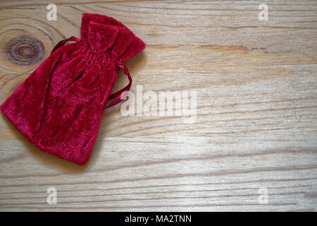 Postcard sample, grenadine gift pouch on wooden background with free copyspace for greeting text. Stock Photo