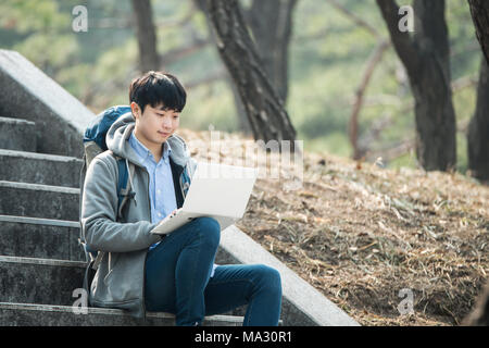 Asian man backpacking using laptop Stock Photo