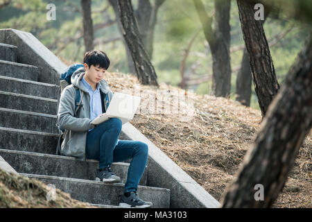 Asian man backpacking using laptop Stock Photo