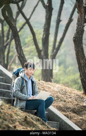 Asian man backpacking using laptop Stock Photo