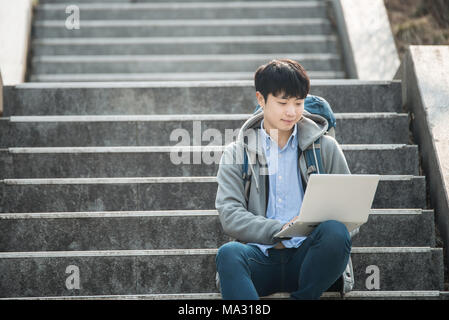 Asian man backpacking using laptop Stock Photo
