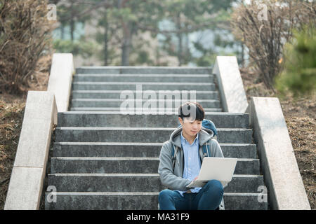 Asian man backpacking using laptop Stock Photo
