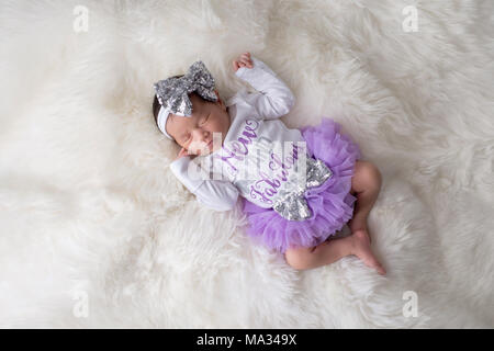 Portrait of a 12 day old newborn baby girl wearing frilly, purple, tutu bloomers and a white onesie that say, 'New and Fabulous'. Shot in the studio o Stock Photo