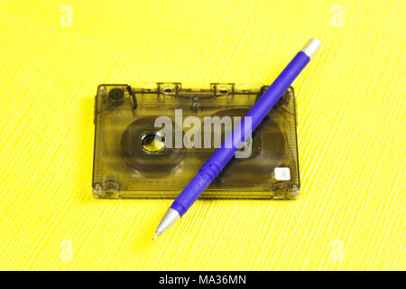 Music of the past. Audio cassette with music of 80 years and a pencil for rewinding tapes of tape on a yellow background Stock Photo