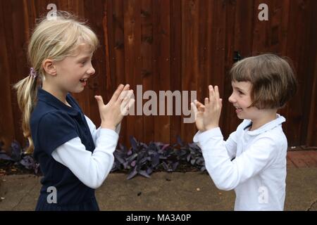 Two girls playing pat a cake Stock Photo