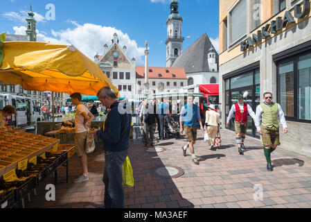 Men in Bavarian dress walk on the busy market in front of the town hall and the church in the old town of Freising, Bavaria, Germany Stock Photo