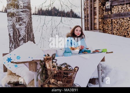 wintertime,young woman wrapped in a blanket eats outside Stock Photo