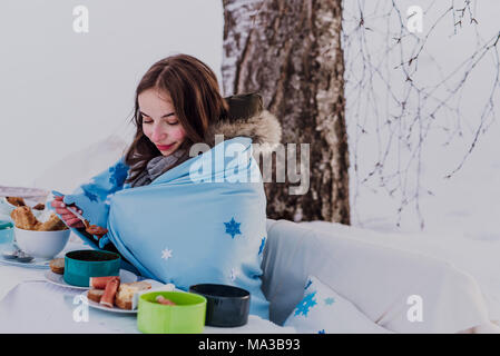 wintertime,young woman wrapped in a blanket eats outside Stock Photo