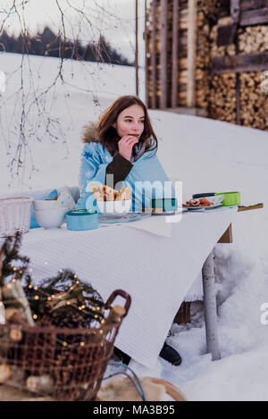 wintertime,young woman wrapped in a blanket eats outside Stock Photo