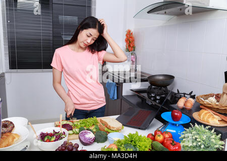 depressed young woman cooking in kitchen room Stock Photo