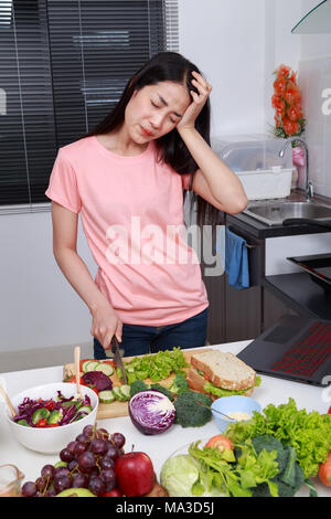 depressed young woman cooking in kitchen room Stock Photo